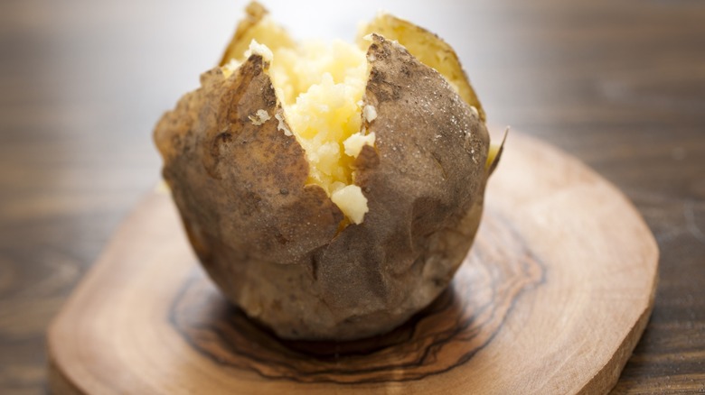 plain split baked potato on wooden dish