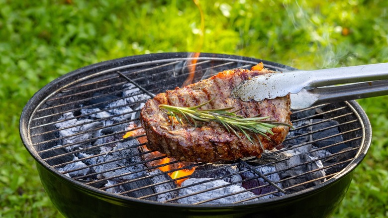 juicy steak on grill with flames and rosemary