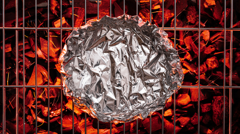 Aluminum foil on grate over hot pieces of coals