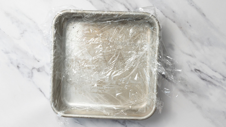 Cake pan covered in plastic wrap