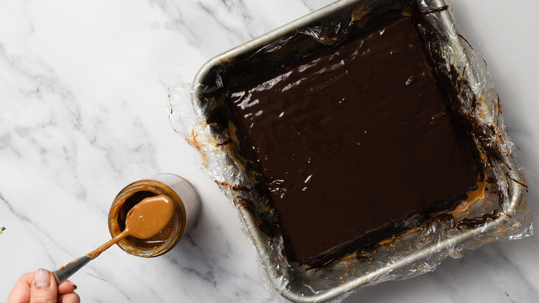 Lifting spoon with dulce de leche from jar