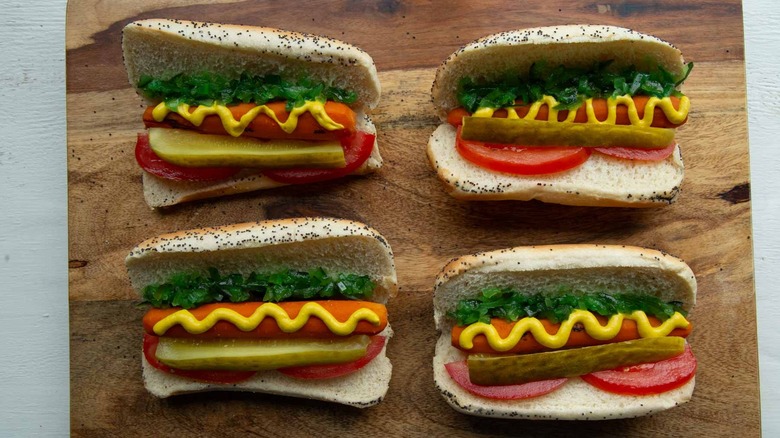 cooked carrots with condiments and garnishes in hot dog buns