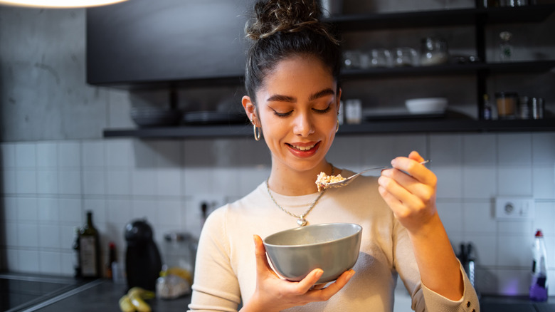 young woman savoring food from bowl