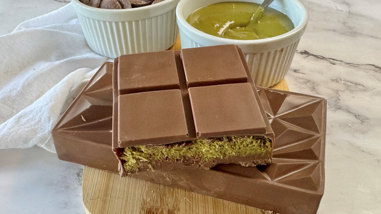 Dubai chocolate bars on wooden board with pistachio cream in bowl