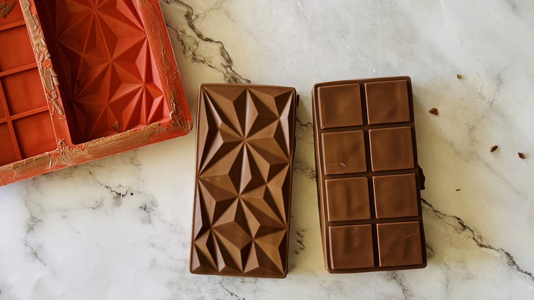 Two chocolate bars next to candy bar mold