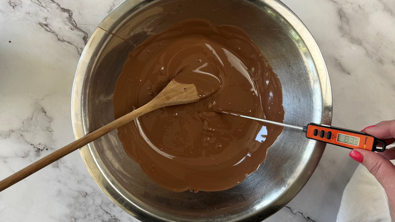 Melted chocolate in bowl with wooden spoon and thermometer