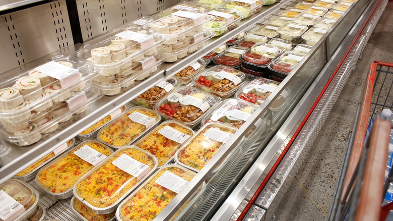 Prepared meals in Costco deli case, overhead view from angle.