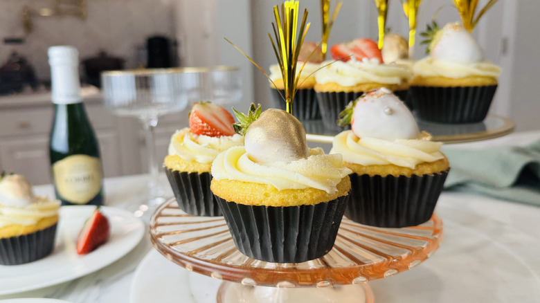 yellow cupcakes with white frosting, strawberries, and other decorations