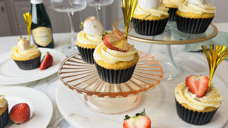 yellow cupcakes with white frosting, strawberries, and other decorations
