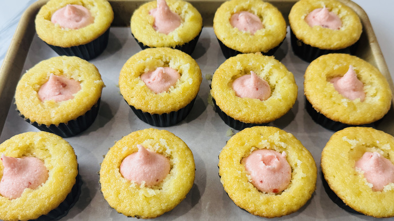 yellow cupcakes with pink frosting in the middle