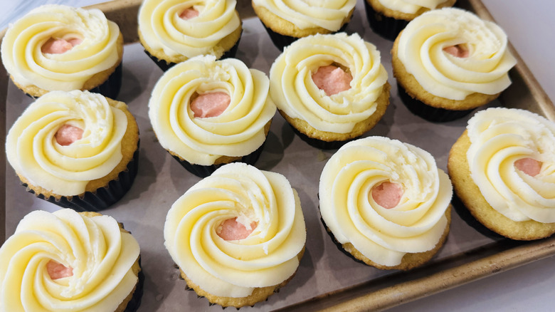 yellow cupcakes with white and pink frosting