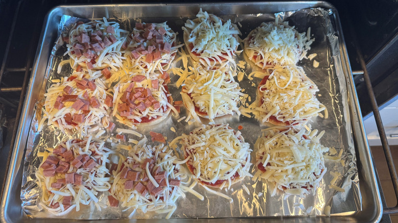 pizza bagel bites on tray going into oven