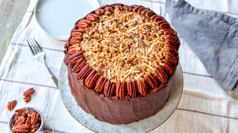 Traditional German chocolate cake on cake stand with pecans and plates