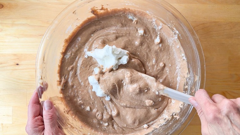 Folding stiffly beaten egg whites into German chocolate cake batter with rubber spatula