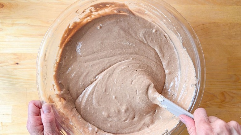 Stirring German chocolate cake batter in glass bowl with rubber spatula