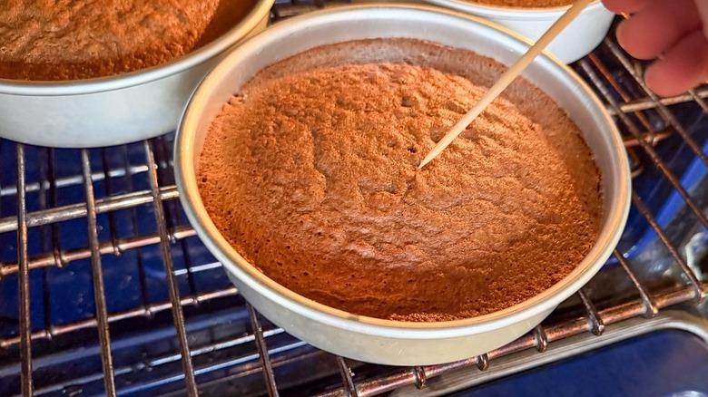 Inserting a wooden pick into a German chocolate cake layer in oven