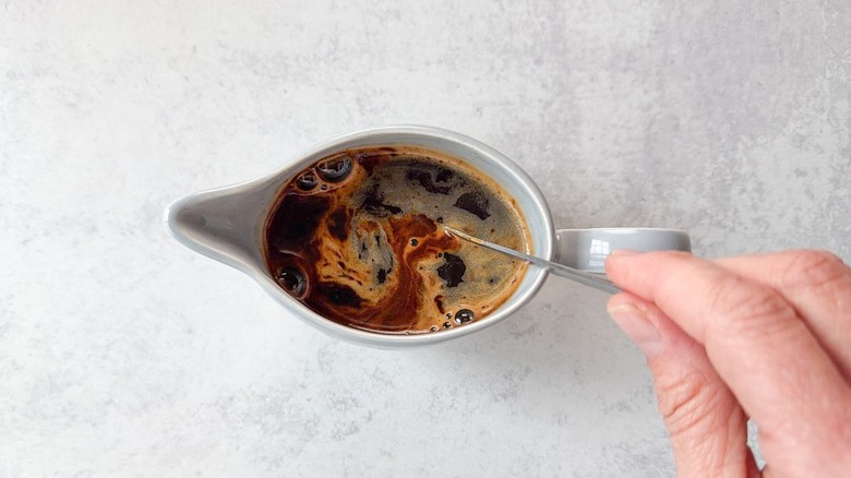 Stirring espresso in a small pitcher with a spoon