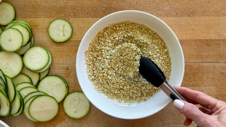 hand with tongs dipping in panko