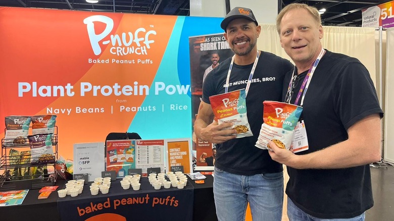 Juan Salinas with person holding bags of P-Nuff Crunch at food expo booth