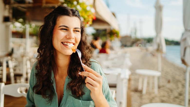 woman eats at a seaside restaurant