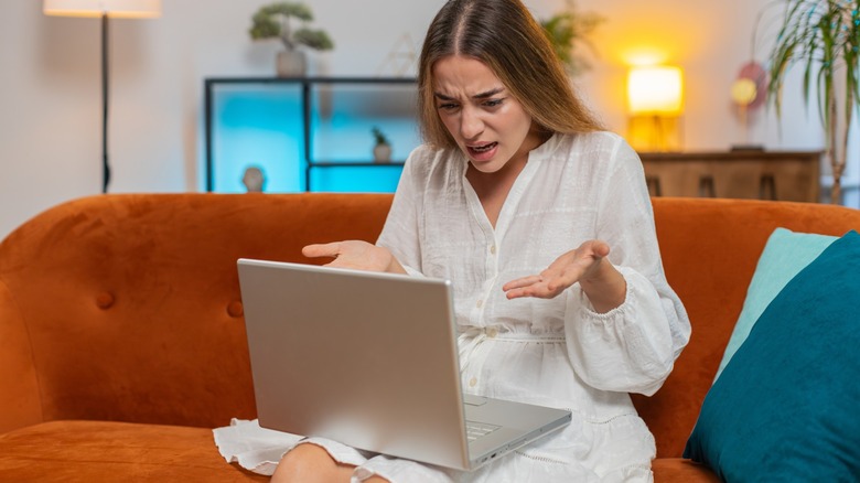 Woman gesturing indignantly at her laptop.
