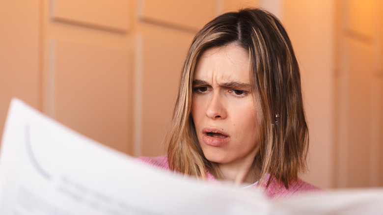 Frustrated woman reading newspaper
