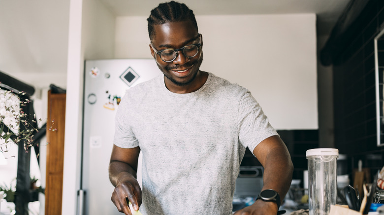 A smiling man cutting fruit while making a healthy meal