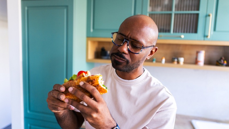man considers the sub he's eating