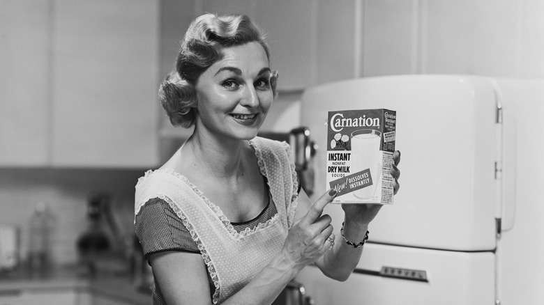 1950s b&w woman holding up Carnation dried milk