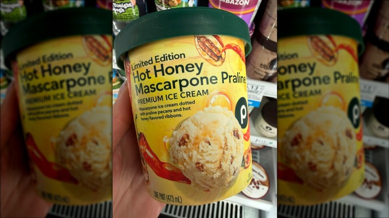 a hand holds a pint of publix hot honey mascapone praline ice cream