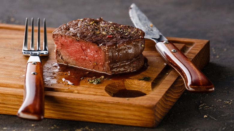 rare filet mignon steak cut on wooden board