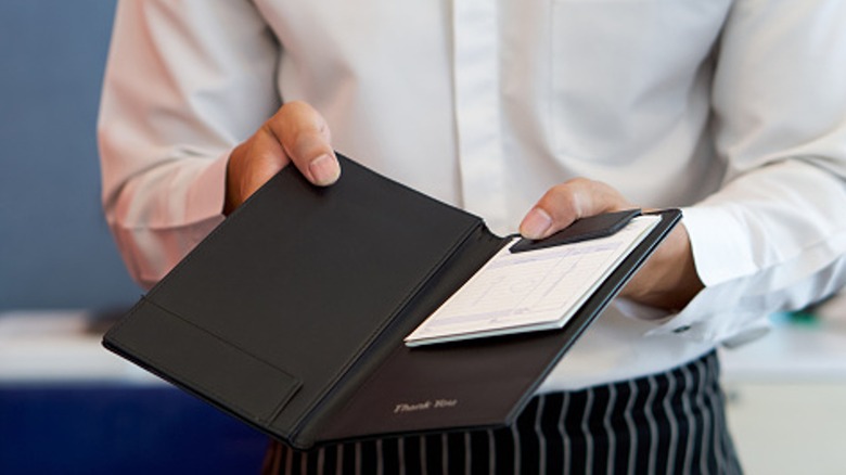 server holding bill at restaurant