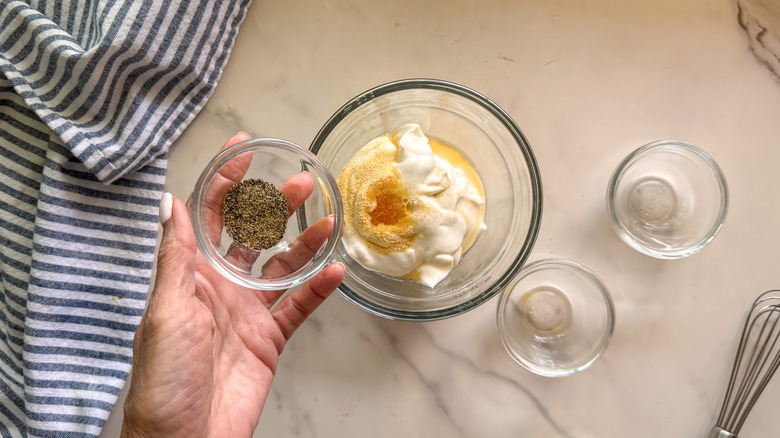 hand adding pepper to bowl