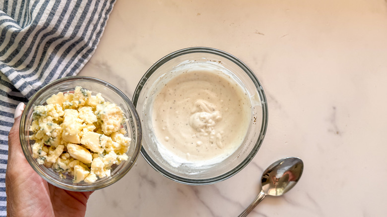 hand adding blue cheese to bowl