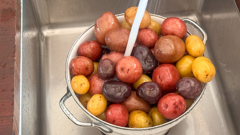 potatoes in colander under sprayer