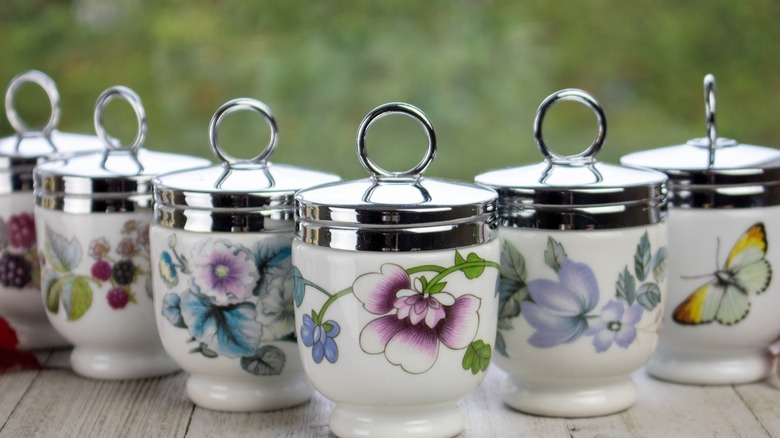 Decorated egg coddlers with silver colored lids