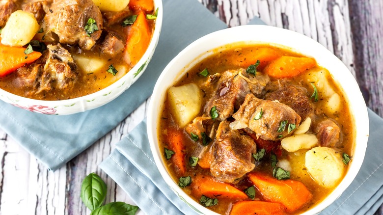lamb stew in white bowls with potatoes, carrots, and onions
