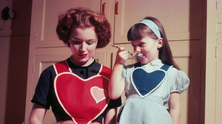 Vintage image of woman and child baking together with heart-shaped aprons.