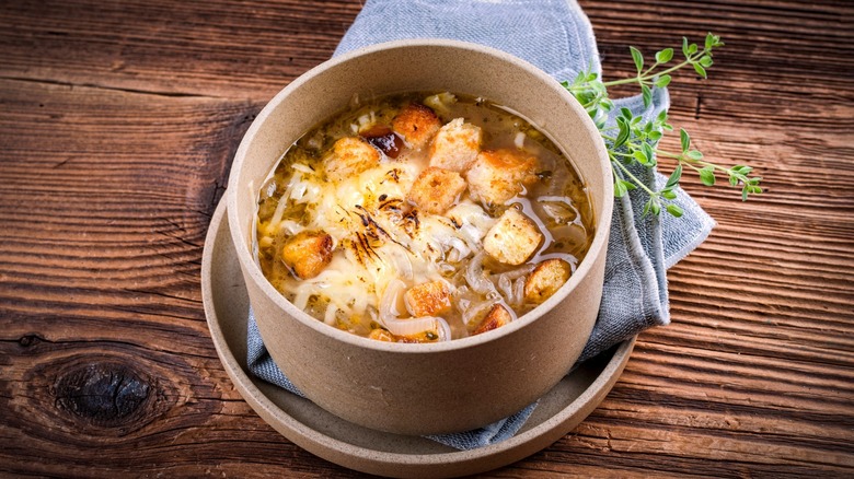 small bowl of french onion soup with napkin and thyme spring