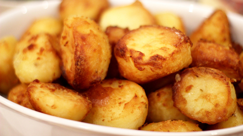 White dish full of golden roast potatoes