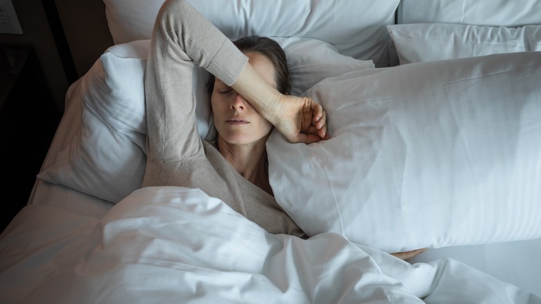 woman lies in bed with a headache