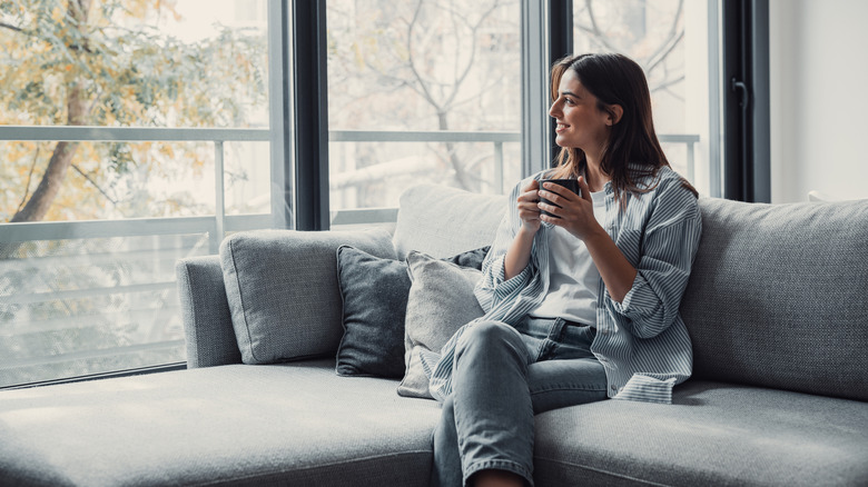 Smiling woman drinking from mug concealed in her hands