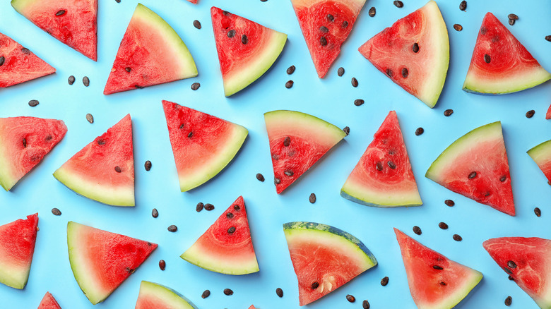Watermelon wedges and watermelon seeds on a light backdrop