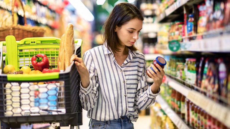 customer reading label on jar in grocery store