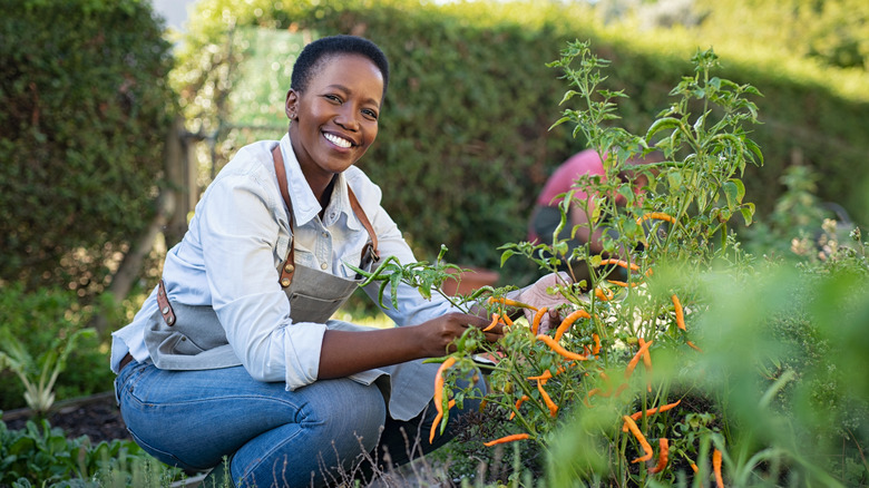 A woman kneeling in garden and smiling