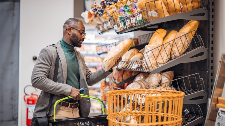 a man examines a loaf of bread at a grocery store bakery