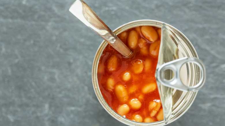 Partially open can of baked beans with a spoon sticking out