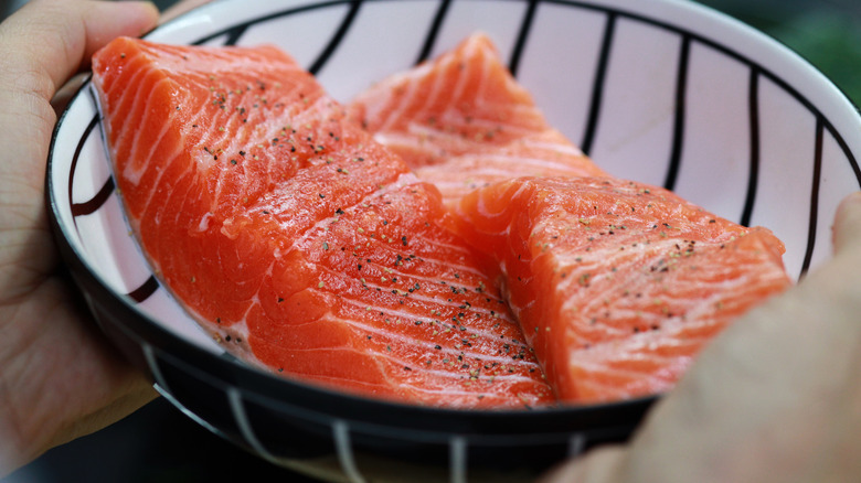 Someone holding a bowl of fresh salmon