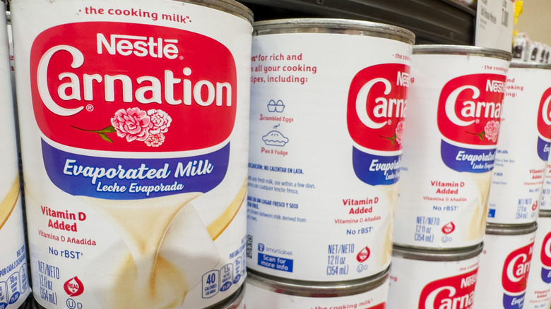 Cans of Nestlé Carnation evaporated milk on a supermarket shelf