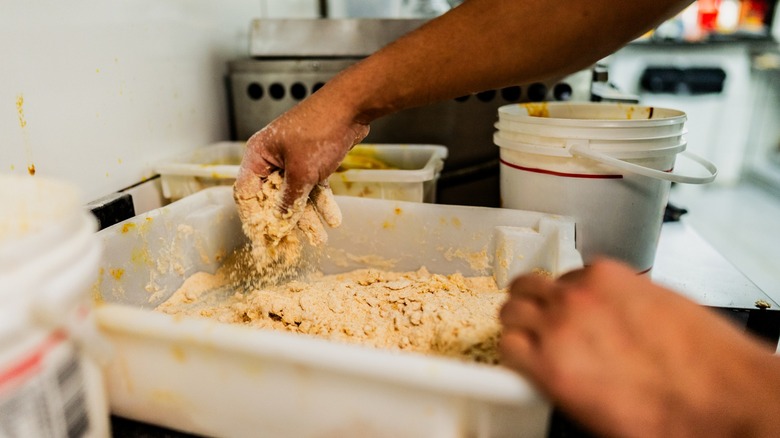 hands bread fried chicken pieces in a seasoned mix